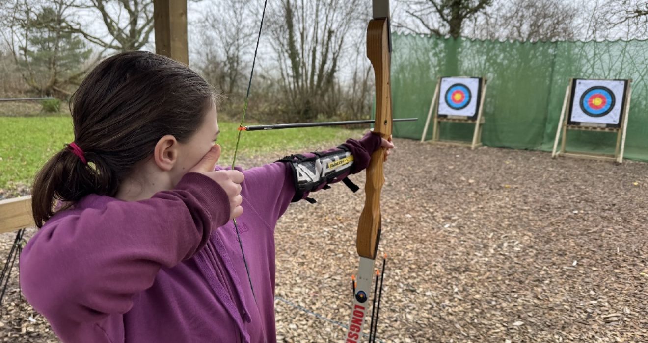 A young girl prepares to shoot an arrow at The Mole Resort