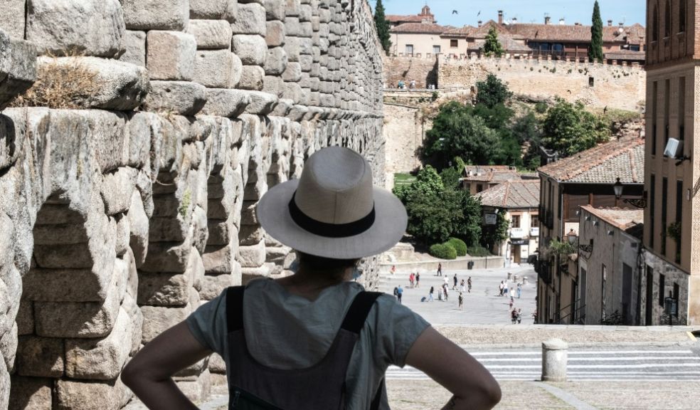 women in blue crew neck t-shirt and brown fedora hat standing near brown concrete ruined buildings