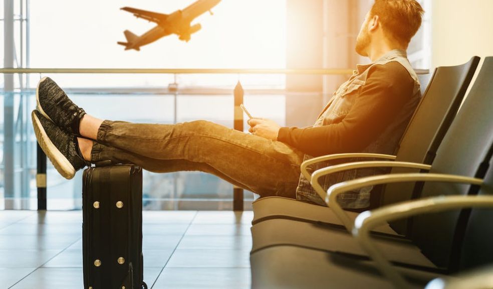 man in departures at airport waiting for flight and plane taking off in distance