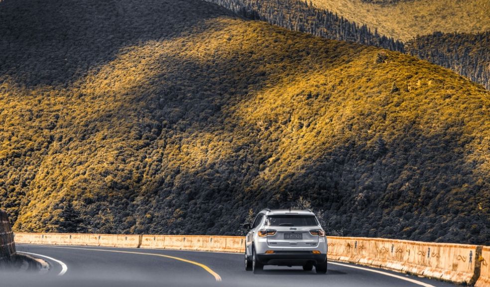 car driving on an open road through mountains