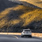 car driving on an open road through mountains
