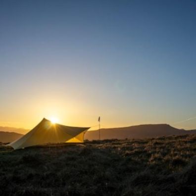 A yellow tent sitting on top of a lush green field photo